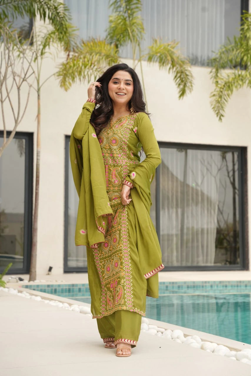 Woman in a green traditional outfit standing by a pool with a building in the background