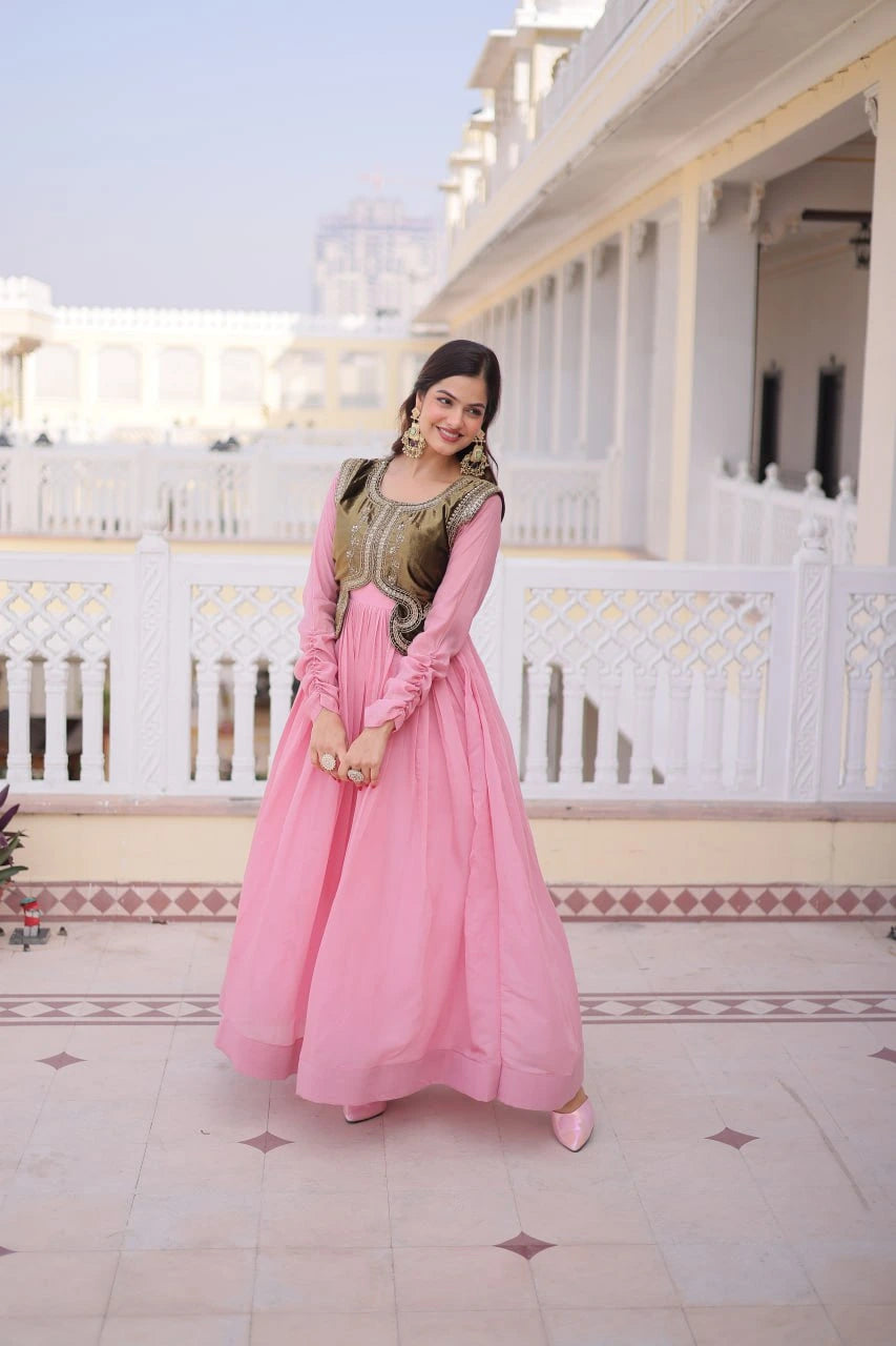 Woman in a pink traditional outfit standing on a balcony with white railings and architectural details.