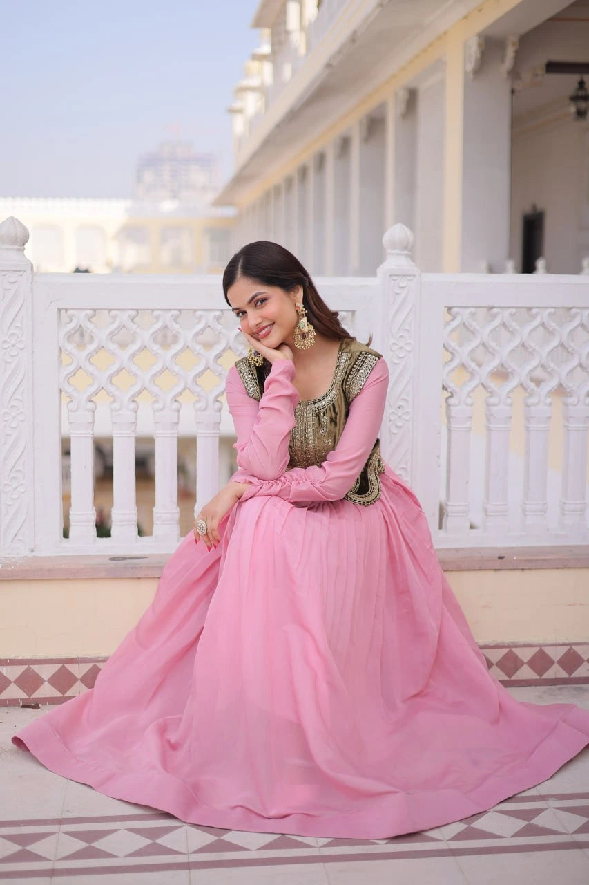 Woman in a pink traditional outfit standing on a balcony with white railings and architectural details.