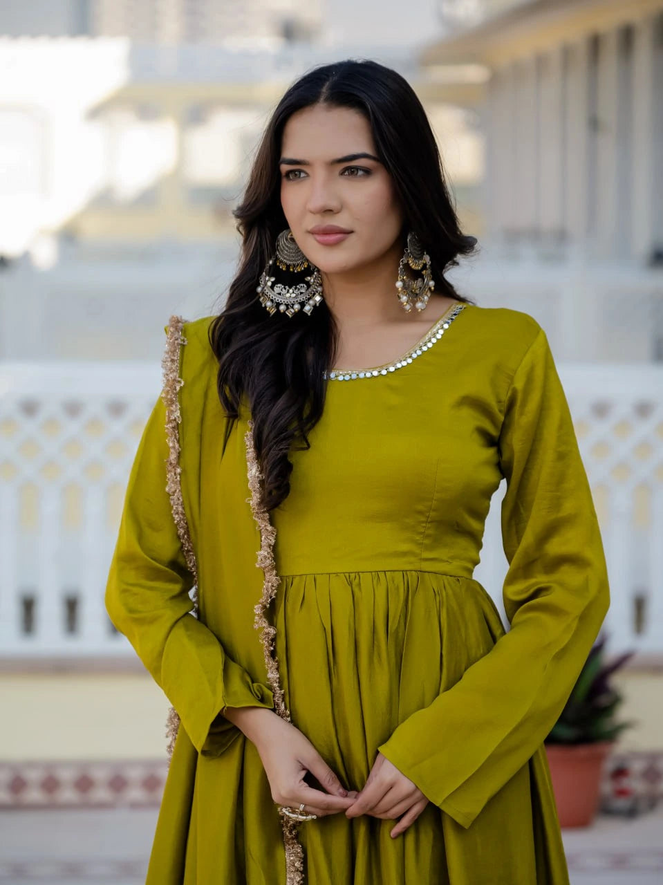 Woman wearing a green traditional outfit with intricate details on a blurred background
