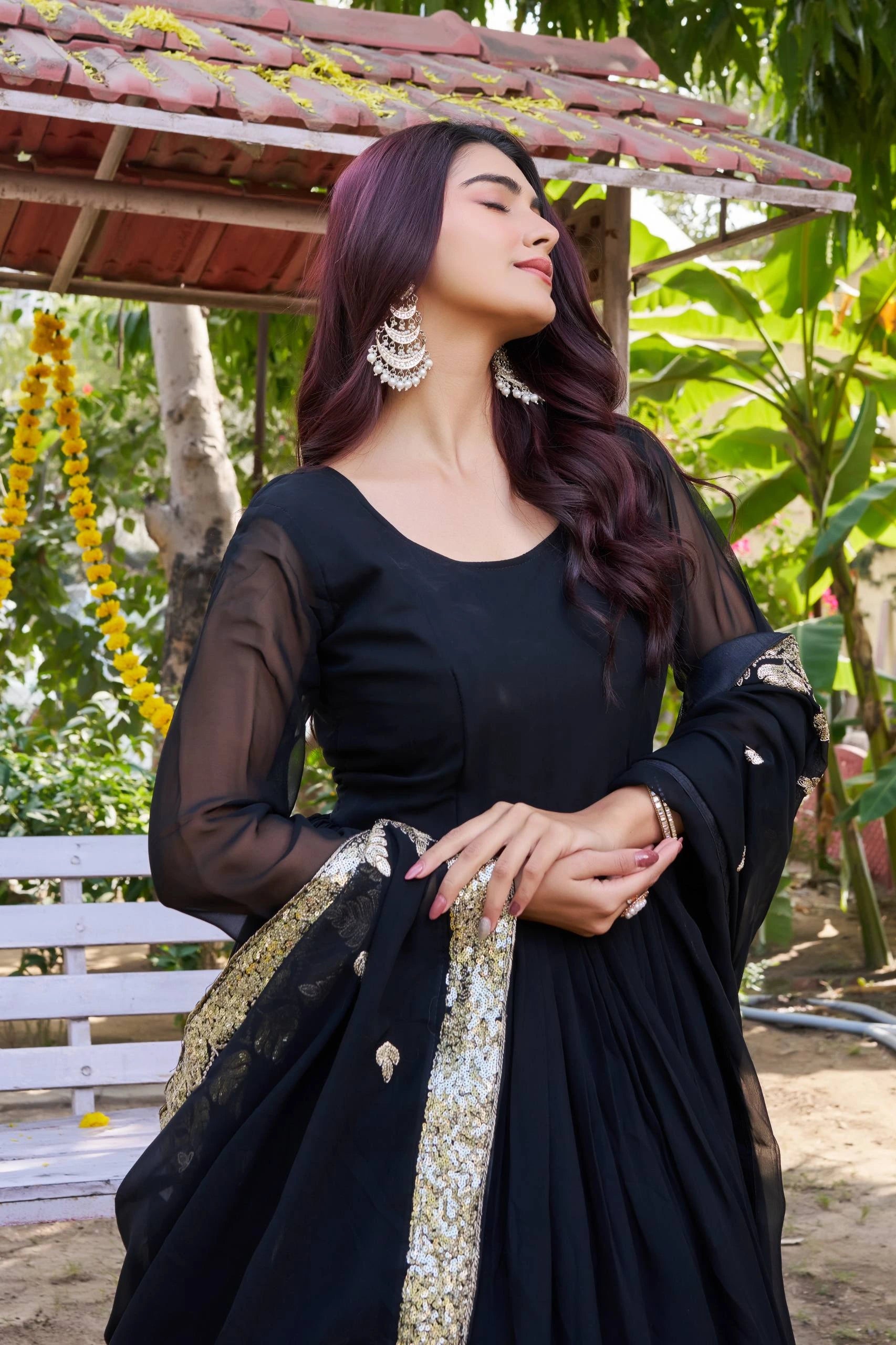 Woman in a black traditional outfit with gold details standing outdoors.