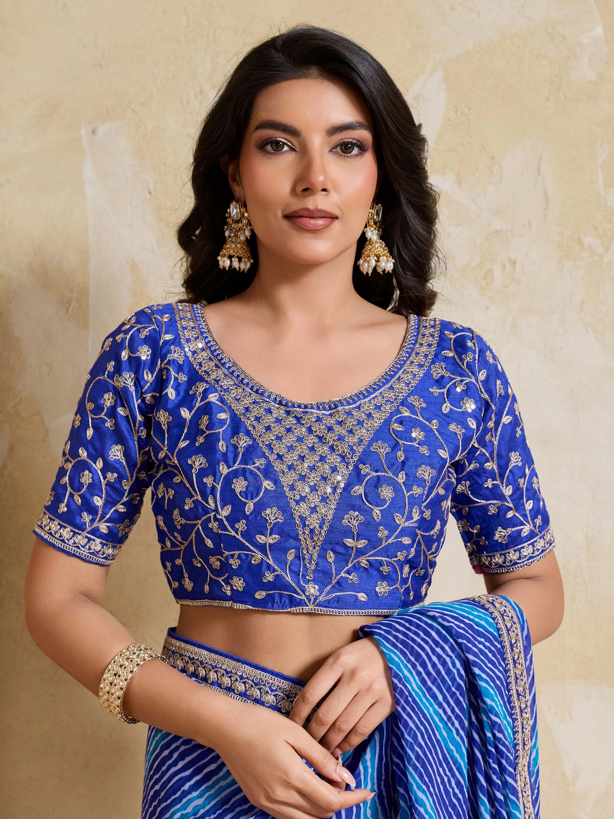 Woman wearing a blue embroidered blouse with a beige background