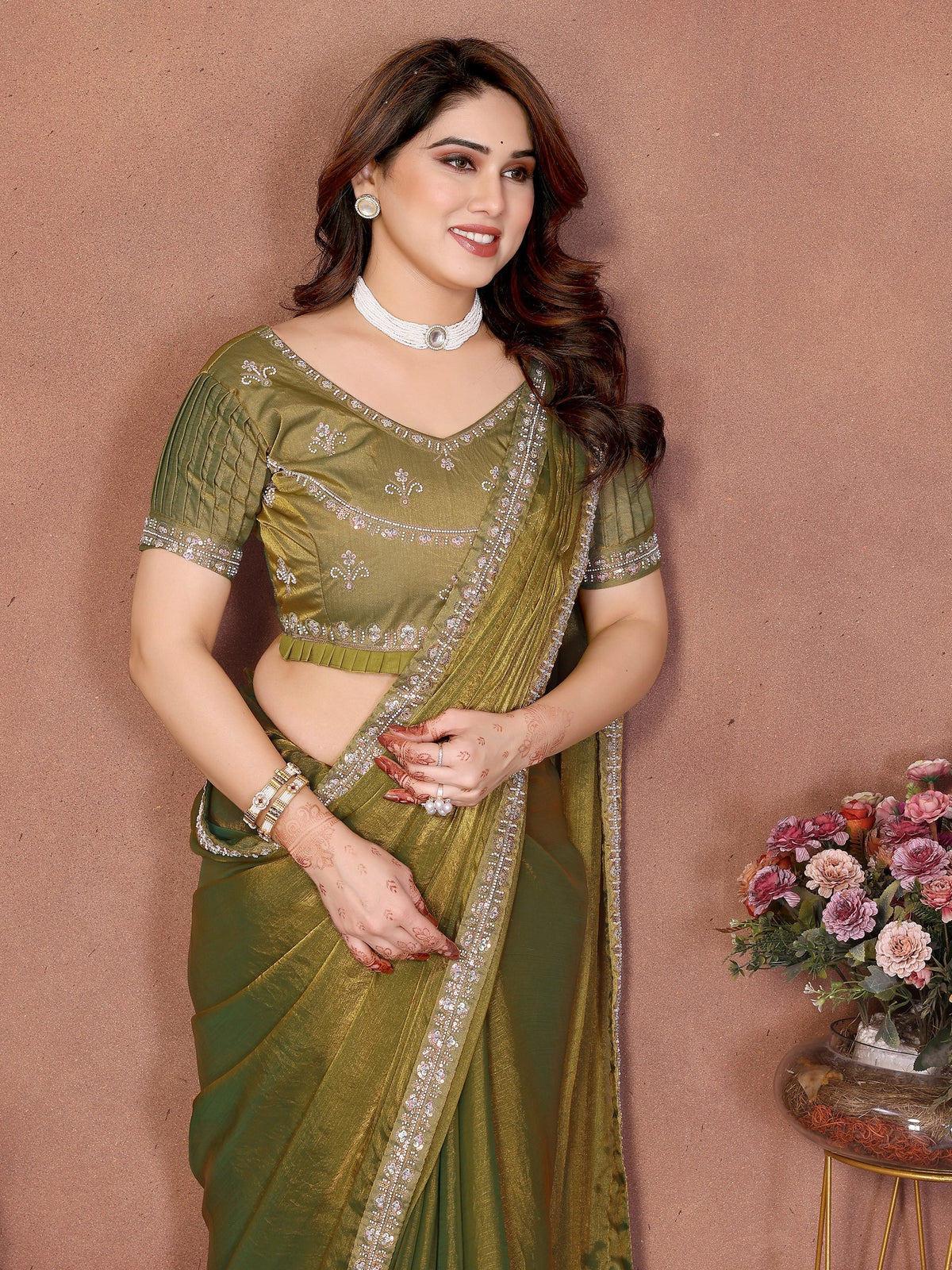 Woman wearing a green saree with a brown background