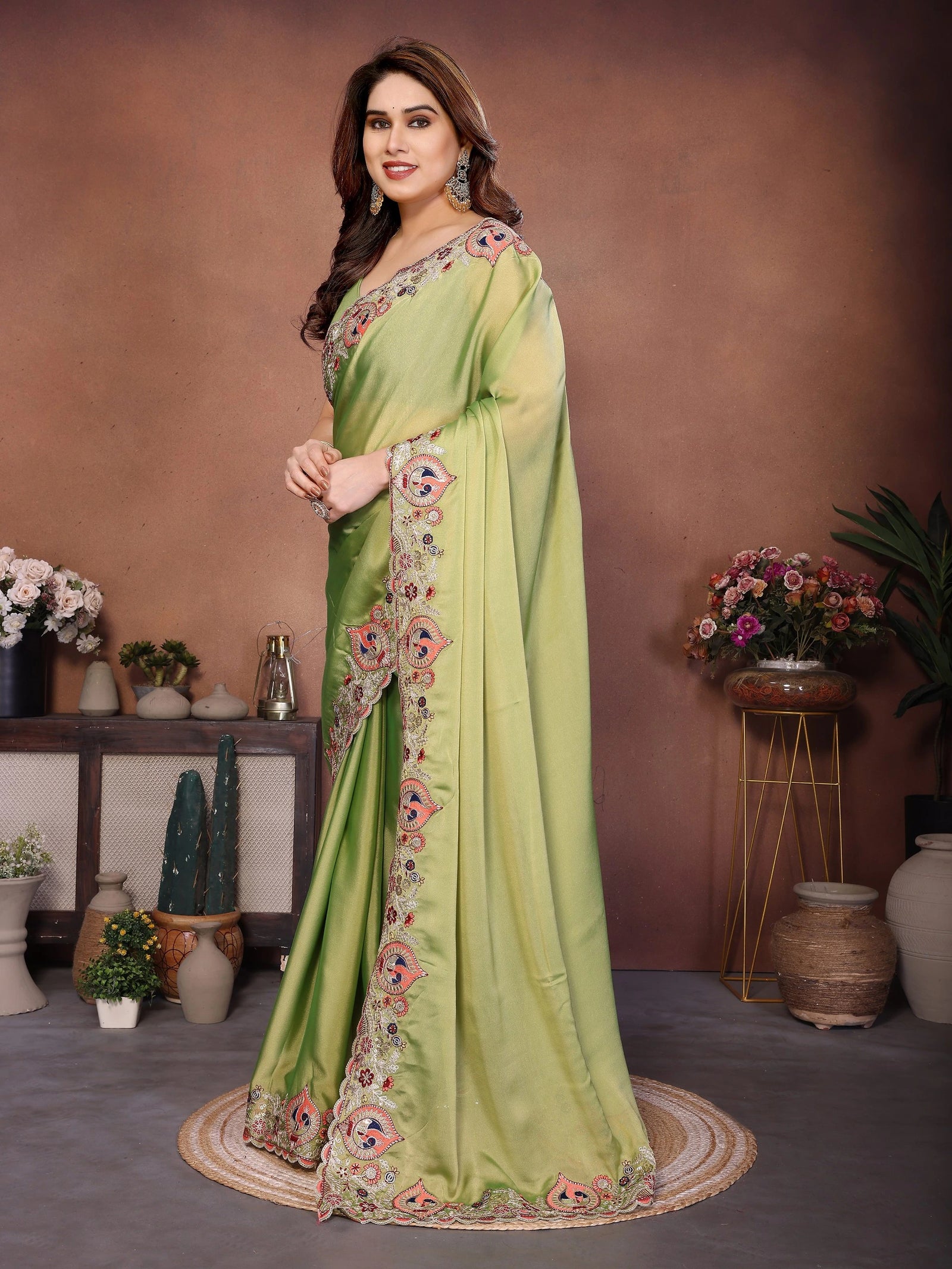 Woman wearing a light green saree with floral embroidery in a decorated room.