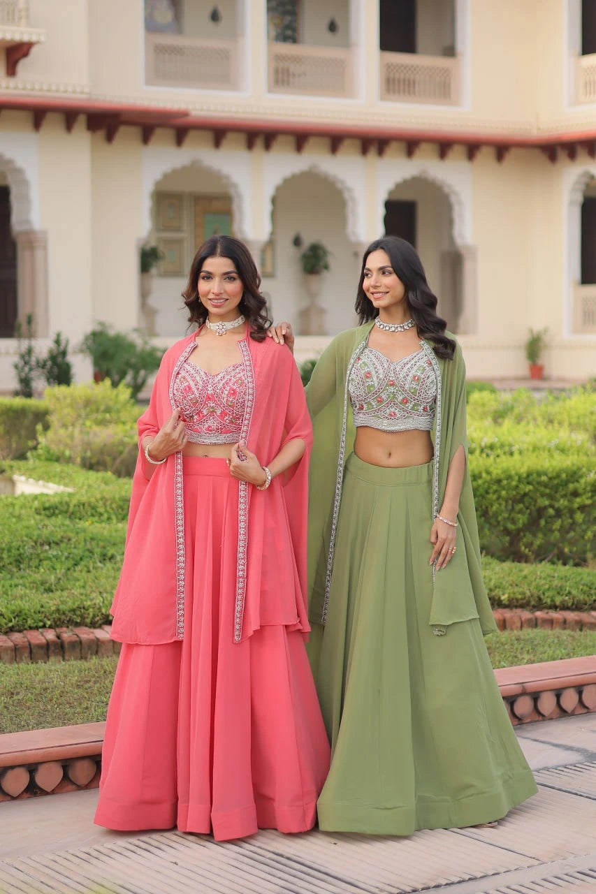 Two women in traditional pink and green outfits standing in a garden.
