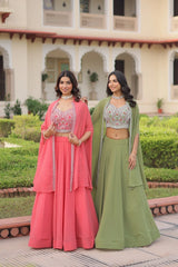 Two women in traditional pink and green outfits standing in a garden.