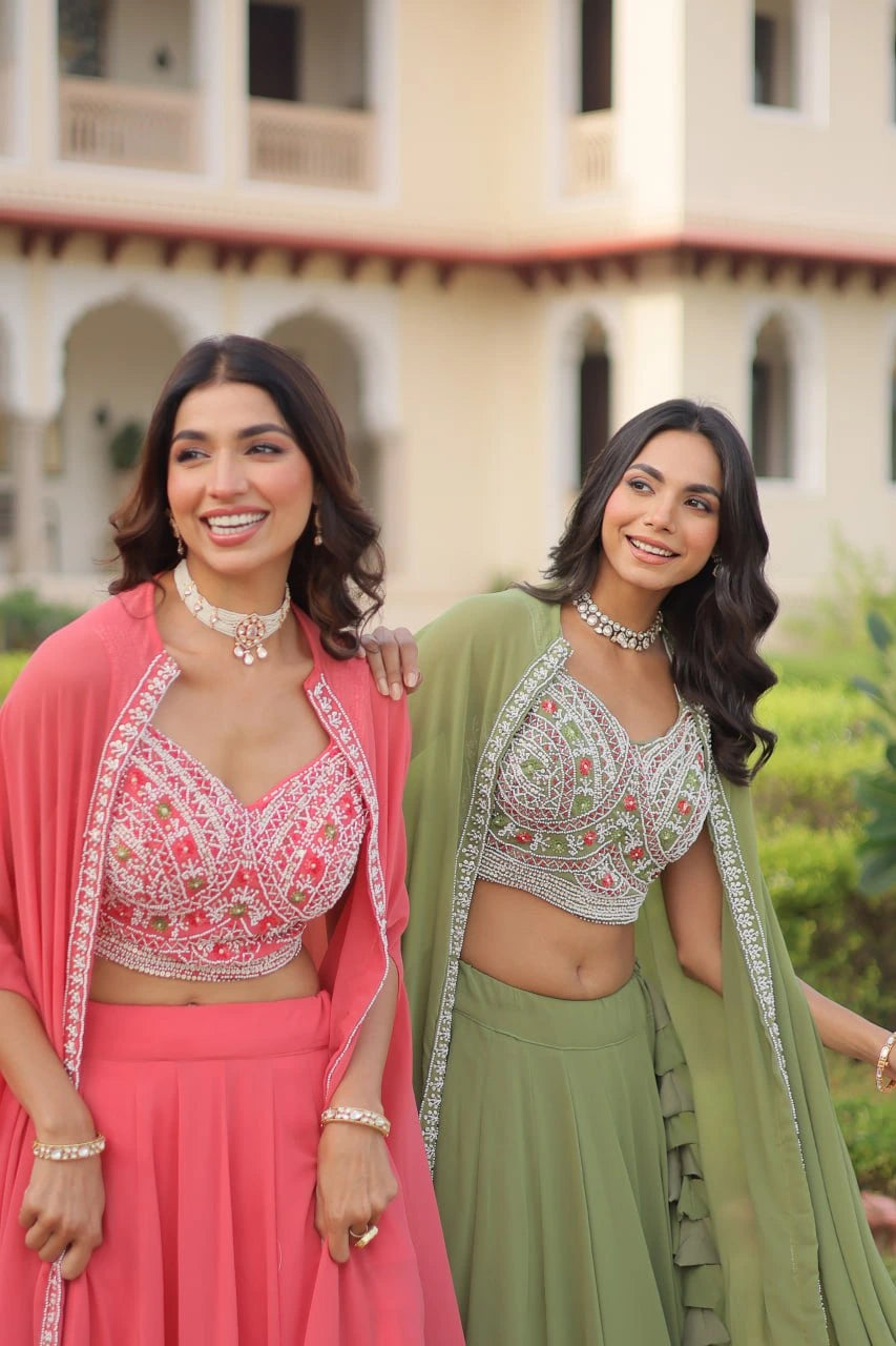 Two women in traditional pink and green outfits standing in front of a building.