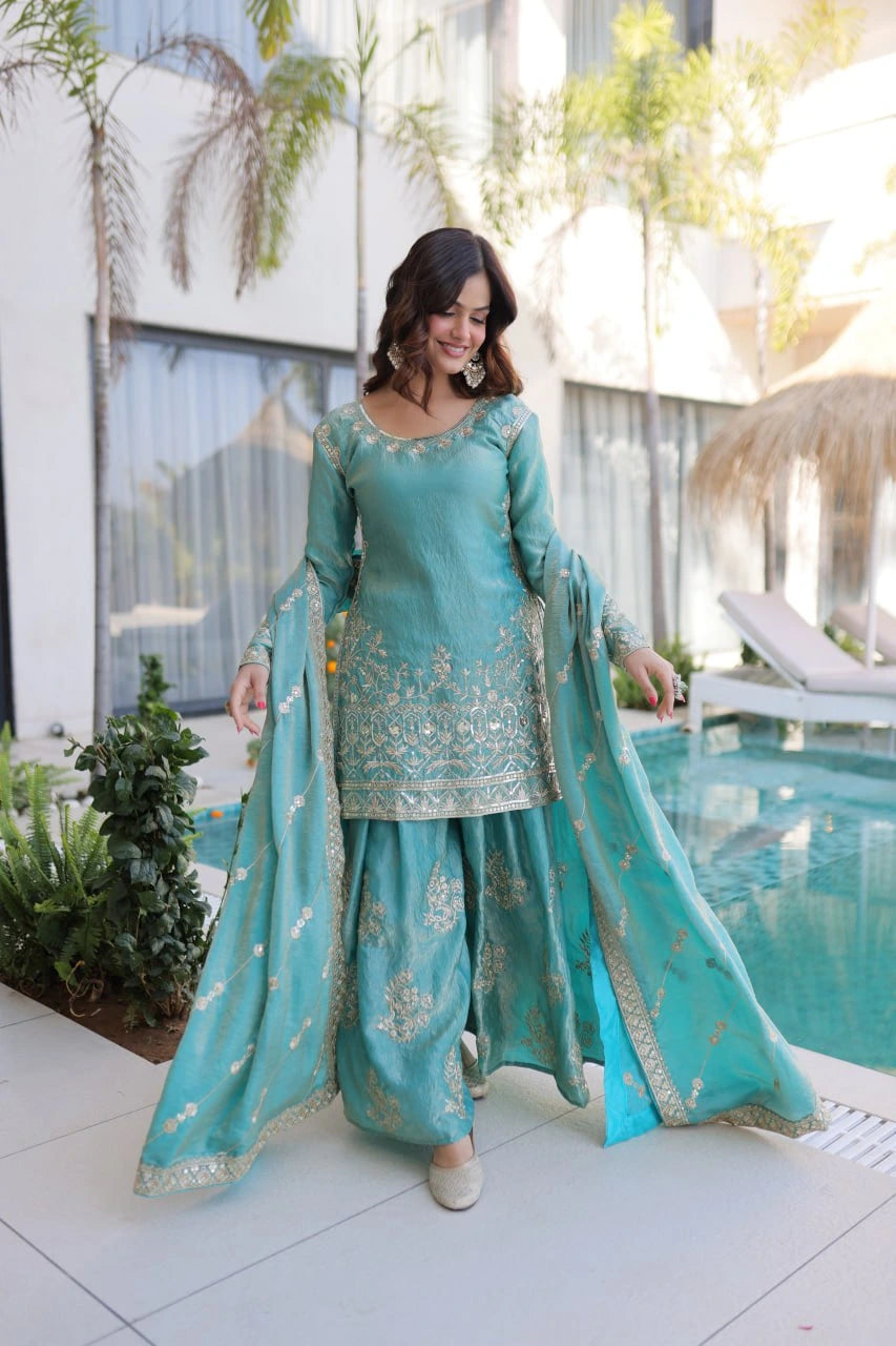 Woman in a turquoise traditional outfit standing by a poolside.