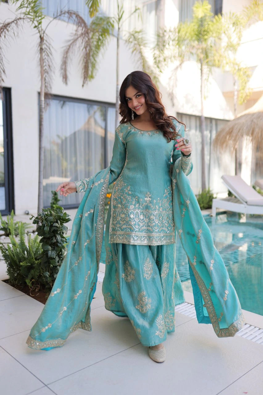 Woman in a turquoise traditional outfit standing by a poolside.