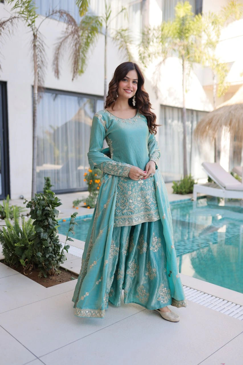 Woman in a teal traditional outfit standing by a poolside.