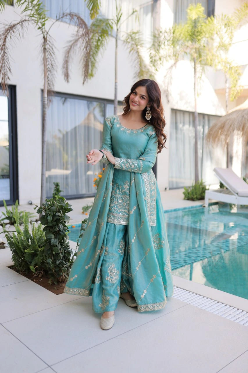 Woman in a teal traditional outfit standing by a poolside.