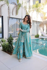 Woman in a teal traditional outfit standing by a poolside.