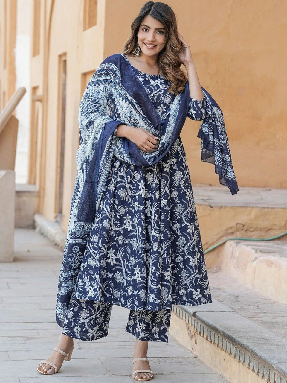 Woman wearing a blue floral dress with a matching shawl in an outdoor setting.