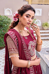 Woman in traditional maroon embroidered saree with floral hairpiece and jewelry outdoors.
