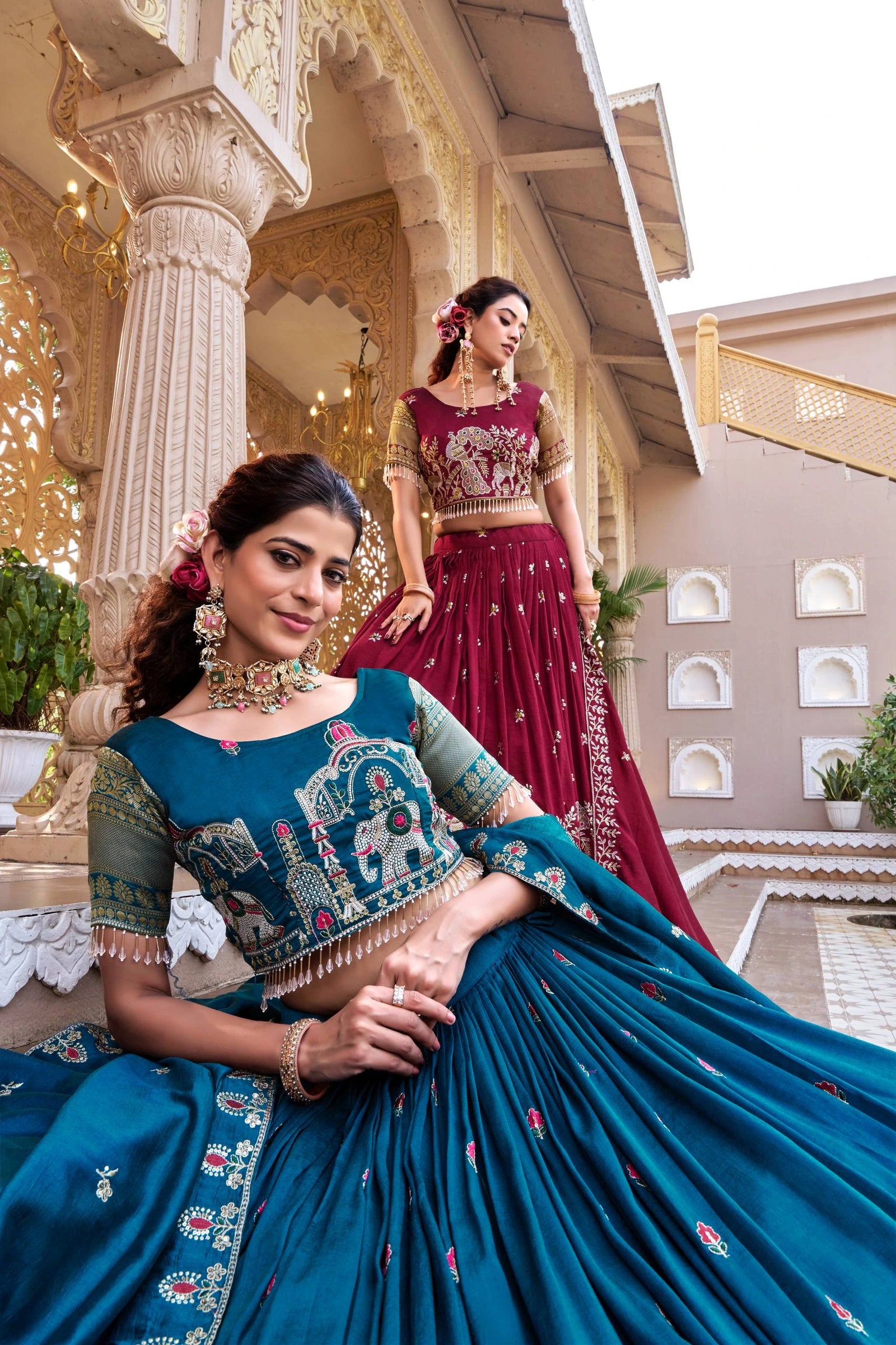 Two women in traditional outfits standing in front of an ornate building.