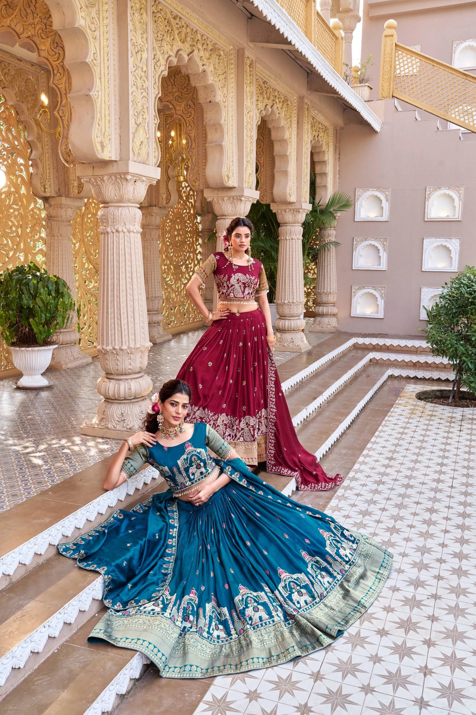 Two women in traditional Indian sarees standing in a decorative indoor setting.