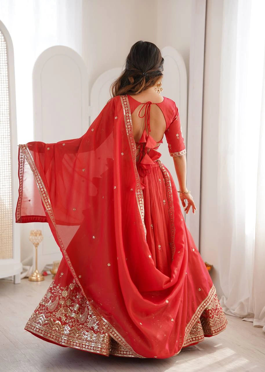 Woman in a red traditional outfit with gold embroidery standing in a bright room.