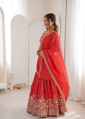 Woman in a red traditional outfit with gold embroidery standing in a bright room.