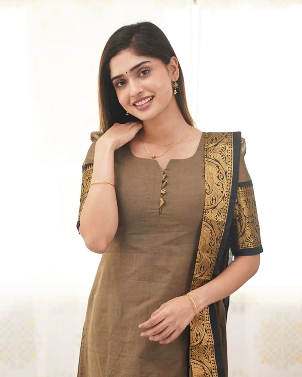 Woman wearing a brown traditional outfit with gold and black details on a white background
