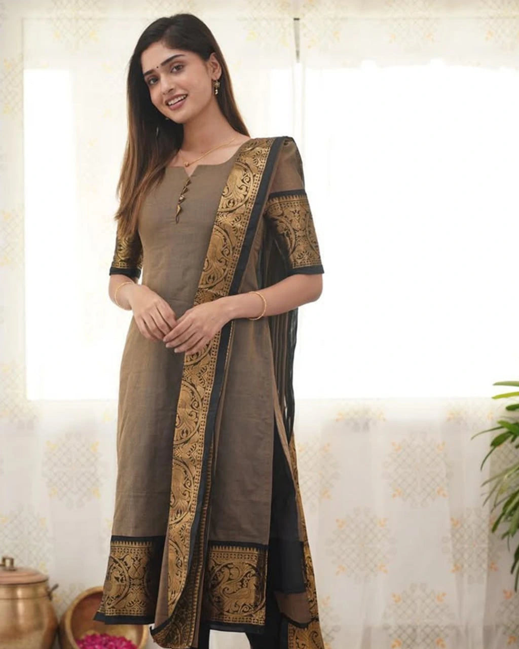 Woman wearing a brown and gold traditional outfit with a matching dupatta.