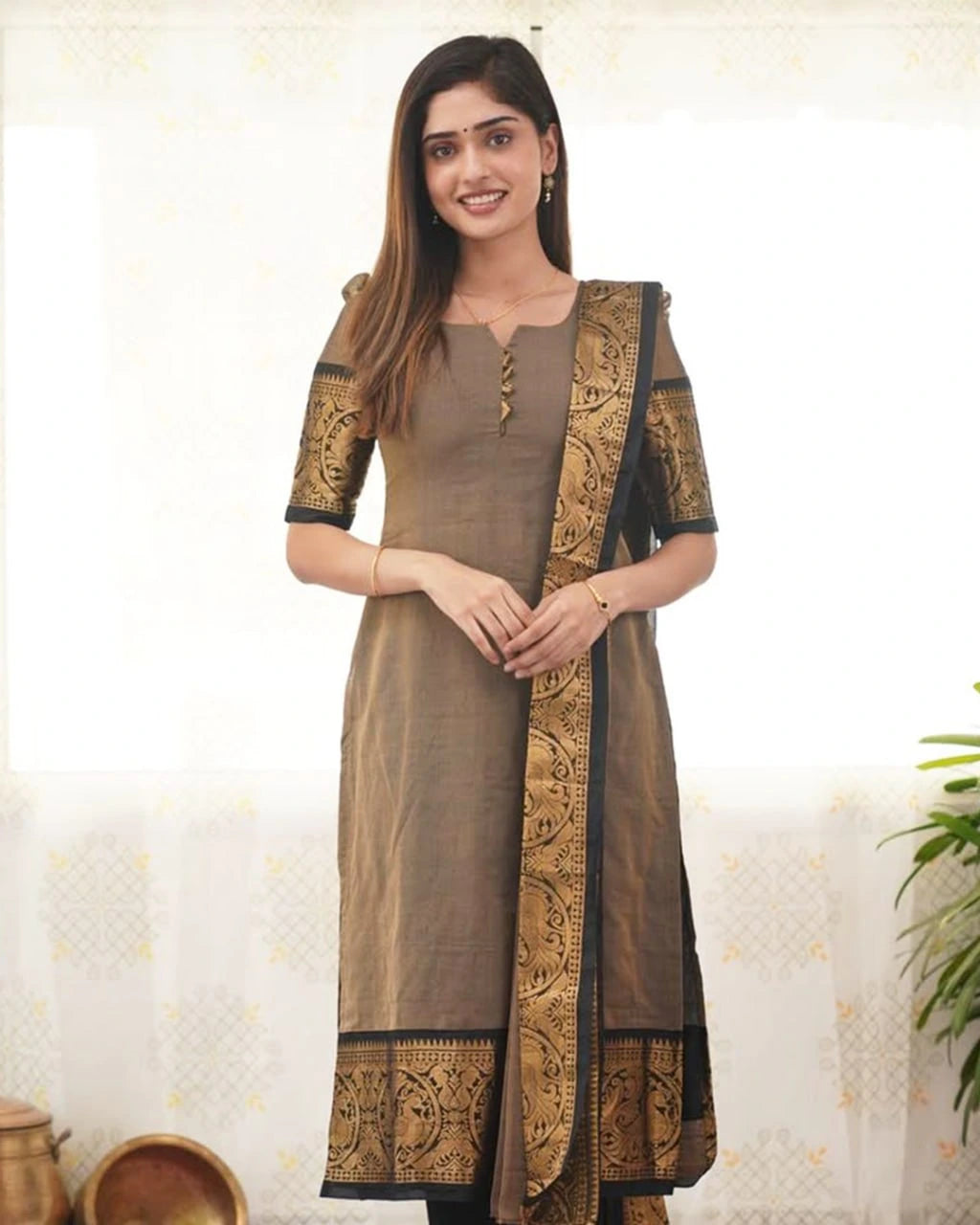 Woman wearing a brown traditional outfit with gold embroidery against a white background