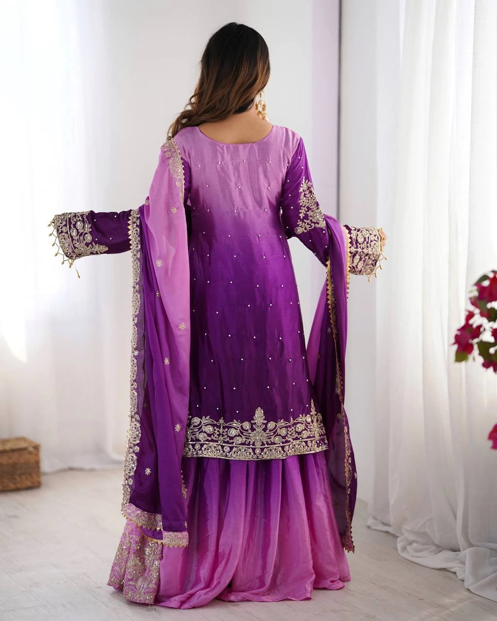 Woman wearing a purple and pink traditional outfit with floral decorations.