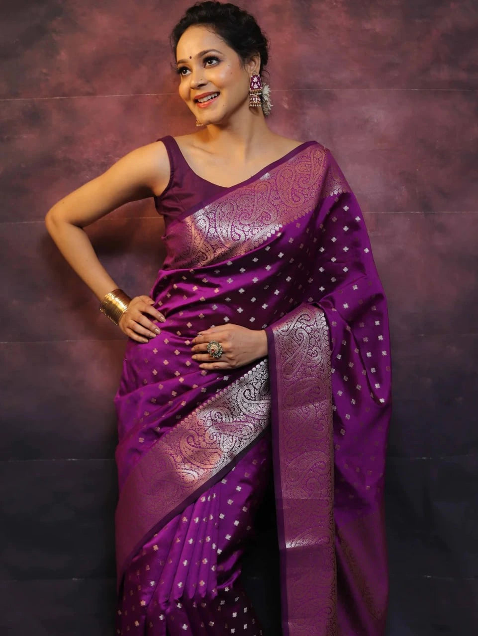 Woman wearing a purple saree with a patterned border against a dark background