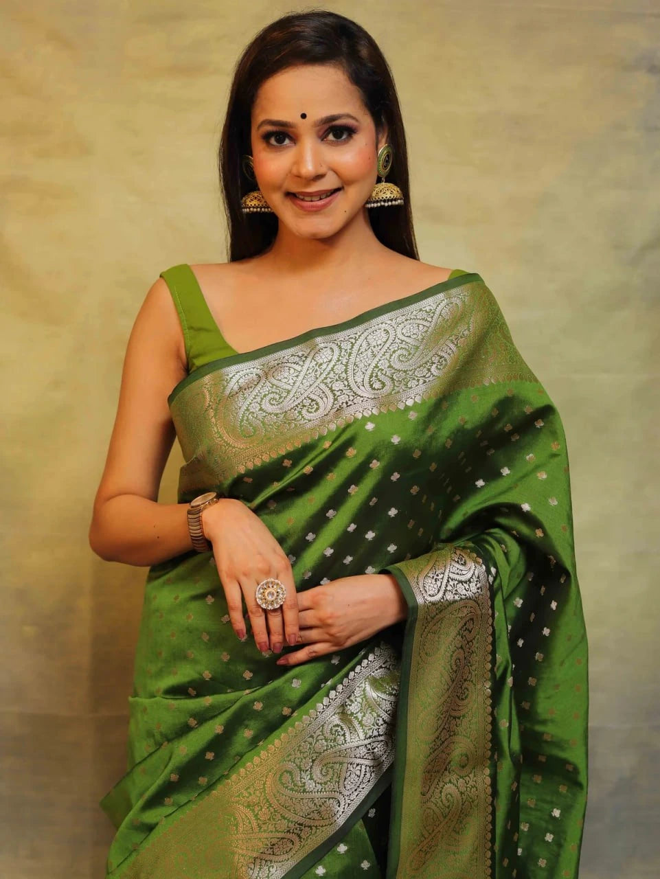 Woman wearing a green saree with silver patterns against a beige background