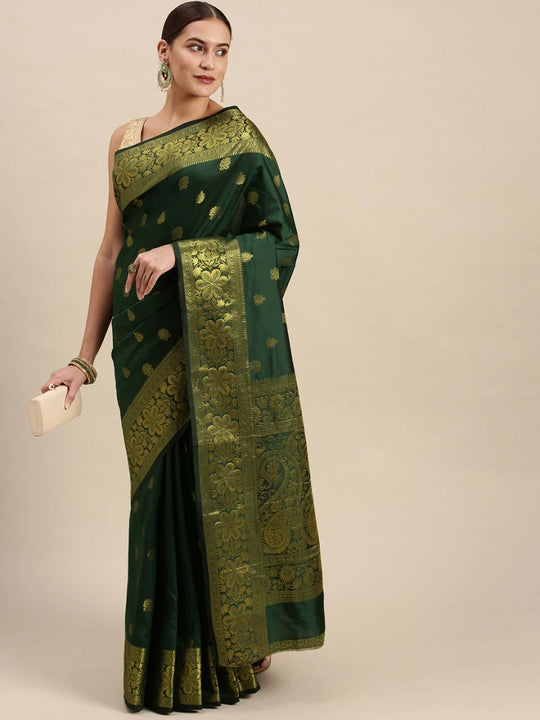 Woman wearing a green saree with gold patterns on a beige background