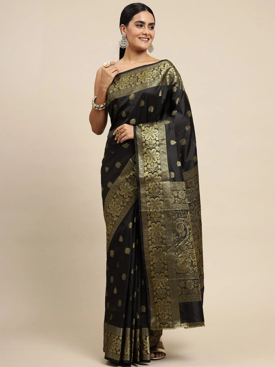 Woman wearing a black saree with gold patterns on a beige background