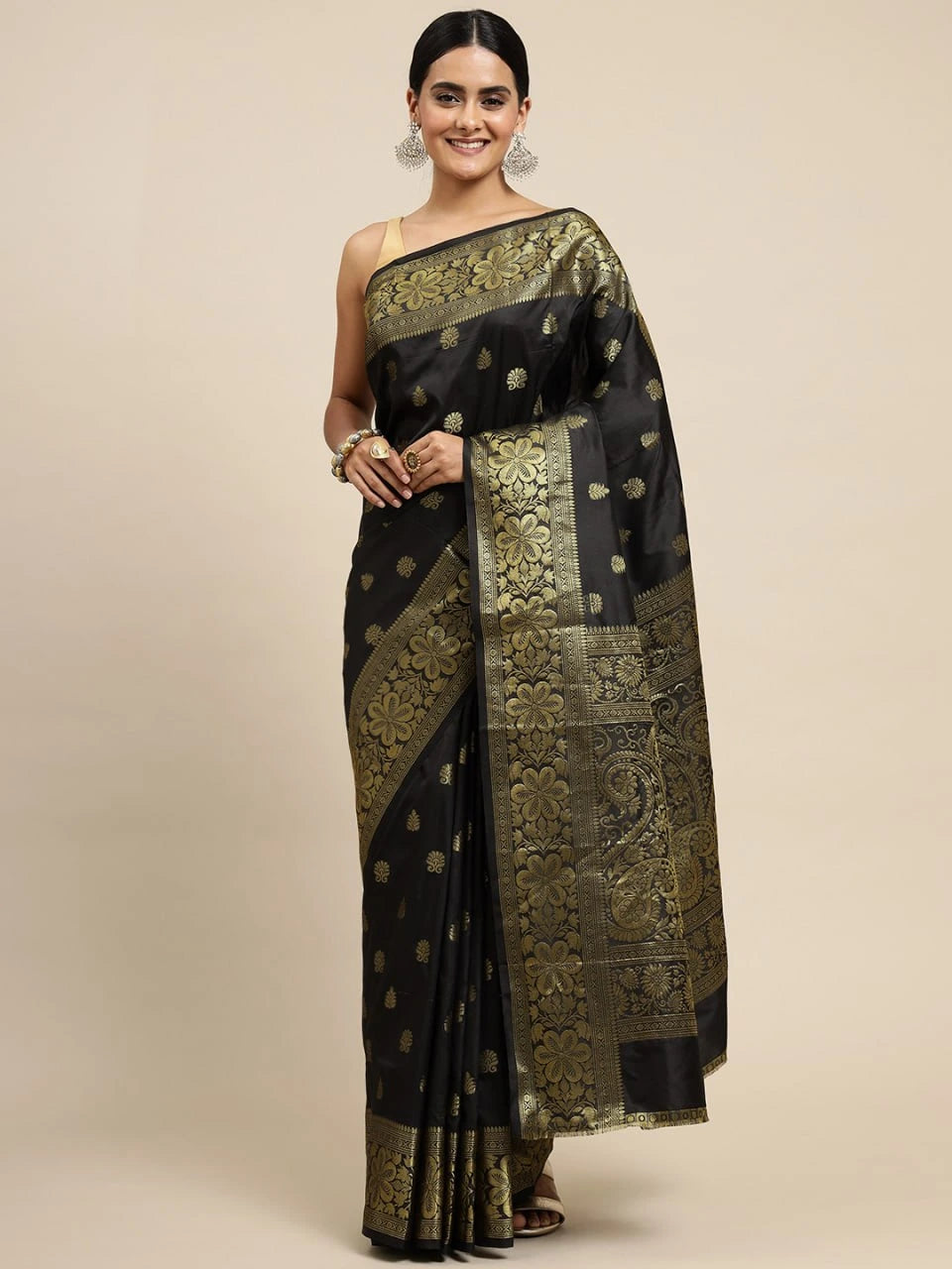 Woman wearing a black and gold saree on a beige background