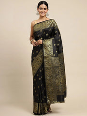 Woman wearing a black and gold saree on a beige background