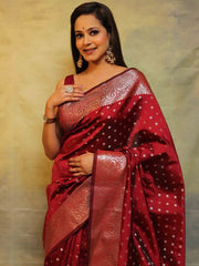 Woman wearing a red saree with intricate patterns against a neutral background