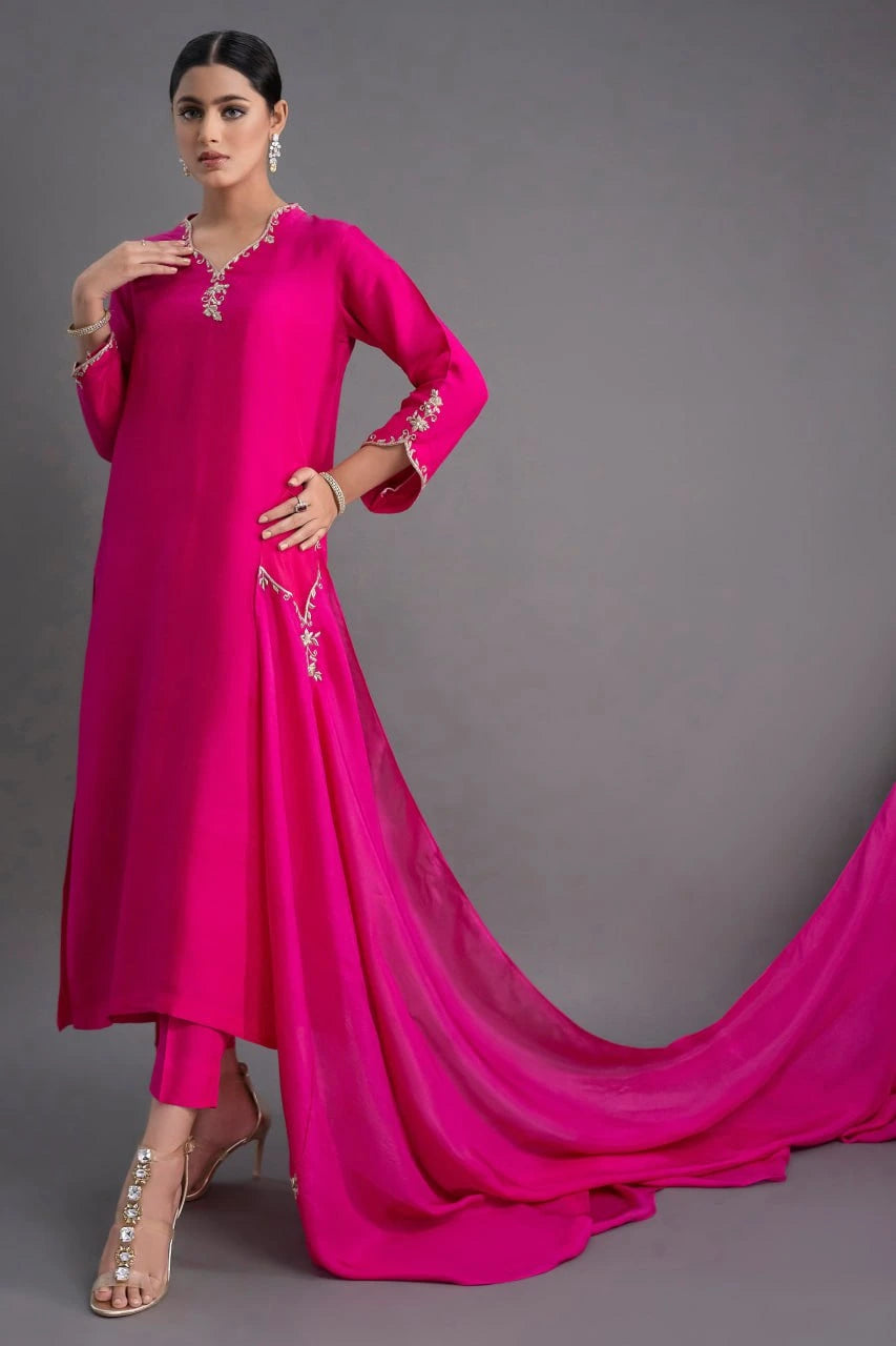 Woman wearing a bright pink traditional outfit with a gray background