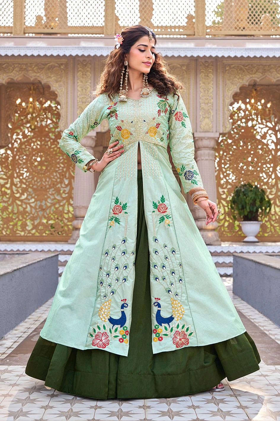 Woman wearing a light green and dark green embroidered traditional outfit in an ornate setting.