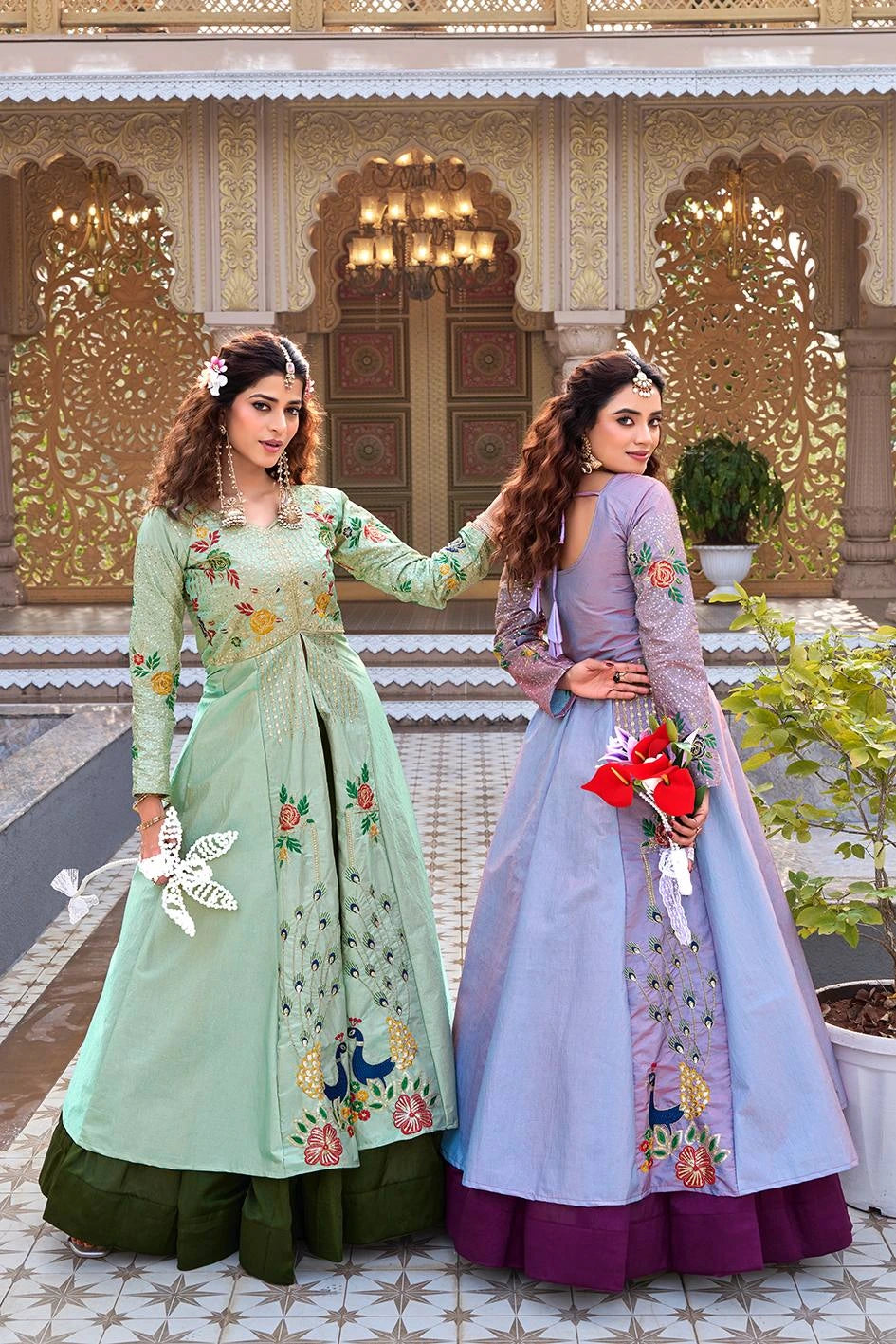 Two women in traditional outfits standing in front of an ornate building.