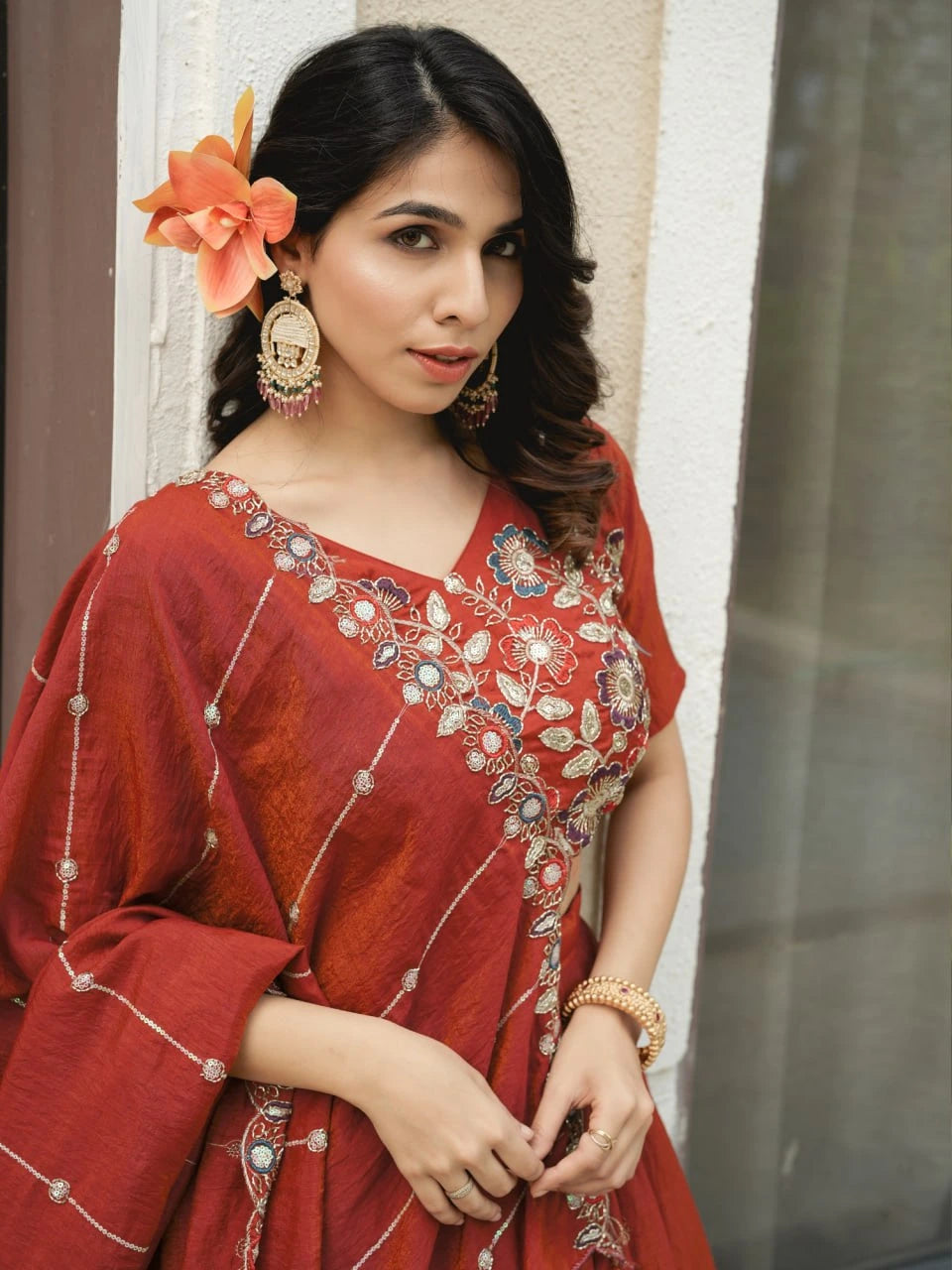 Woman in a red traditional outfit with floral decorations indoors