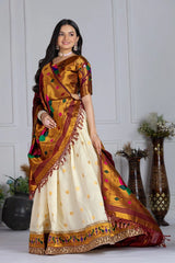 Woman wearing a traditional saree with a white and gold design, standing against a white wall.