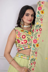 Woman wearing a light green embroidered saree with a floral border.