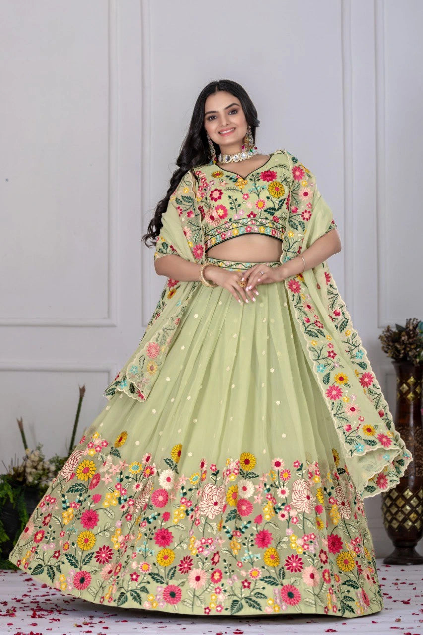 Woman wearing a light green floral embroidered lehenga against a white wall.
