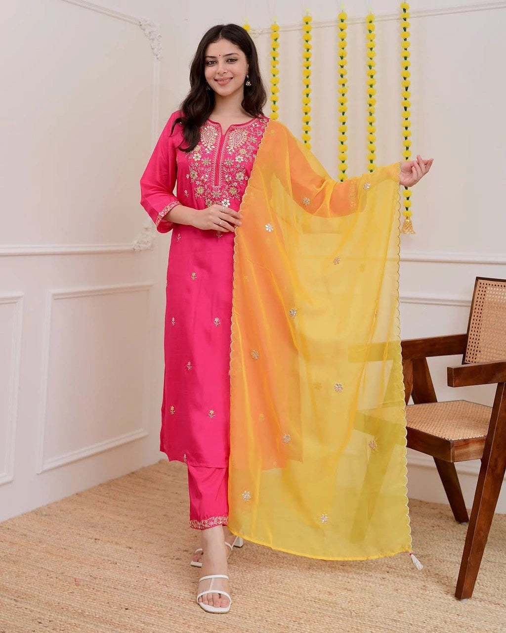 Woman in pink traditional outfit with yellow dupatta indoors