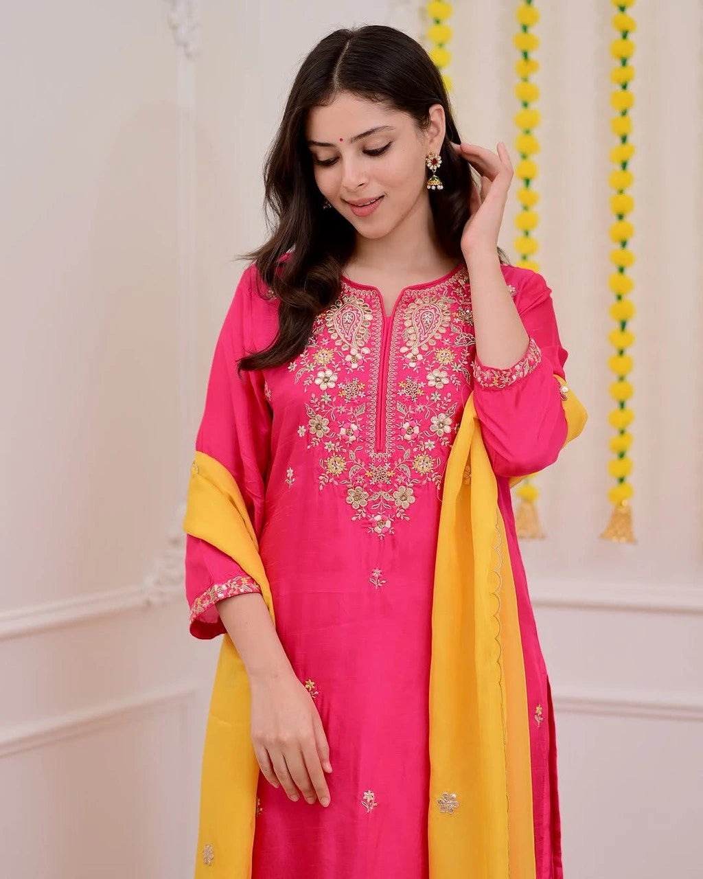 Woman wearing a pink and yellow traditional outfit with embroidery.