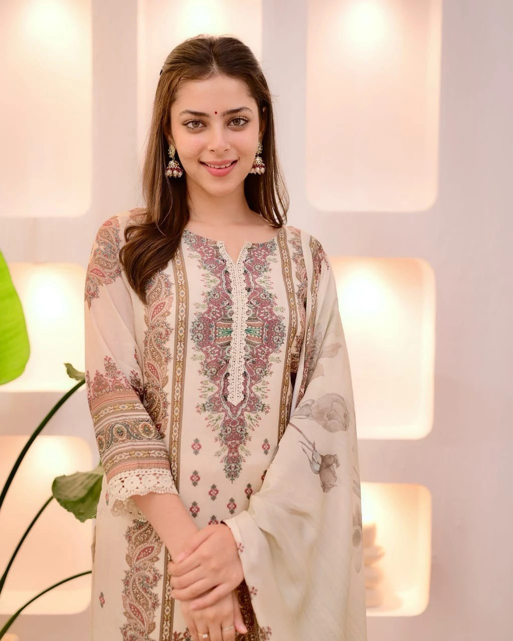 Woman wearing a traditional embroidered outfit with a neutral background