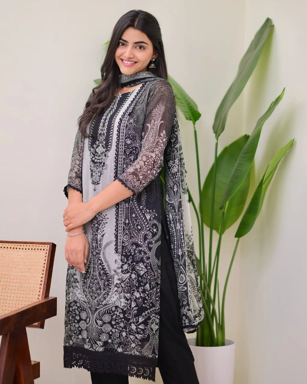 Woman wearing a black and white patterned kurta with a plant in the background