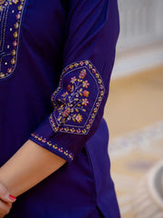 Close-up of a purple garment with intricate floral embroidery on a blurred background