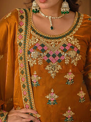 Close-up of a person wearing an orange embroidered outfit with jewelry.