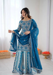 Woman wearing a blue and white traditional outfit with a matching dupatta in a well-lit room.