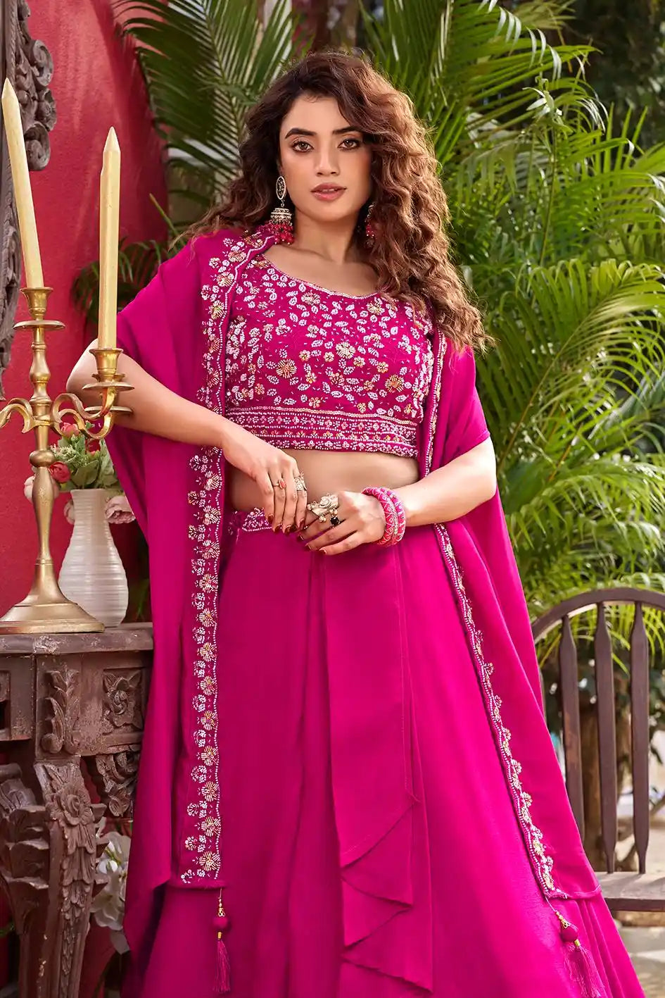Woman in a bright pink traditional outfit with intricate designs, standing outdoors.