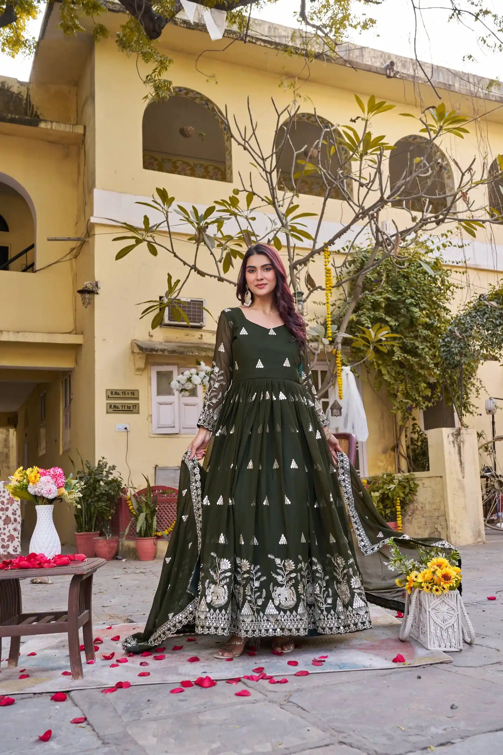 Woman in a green and white patterned dress standing in front of a building with decorative elements.