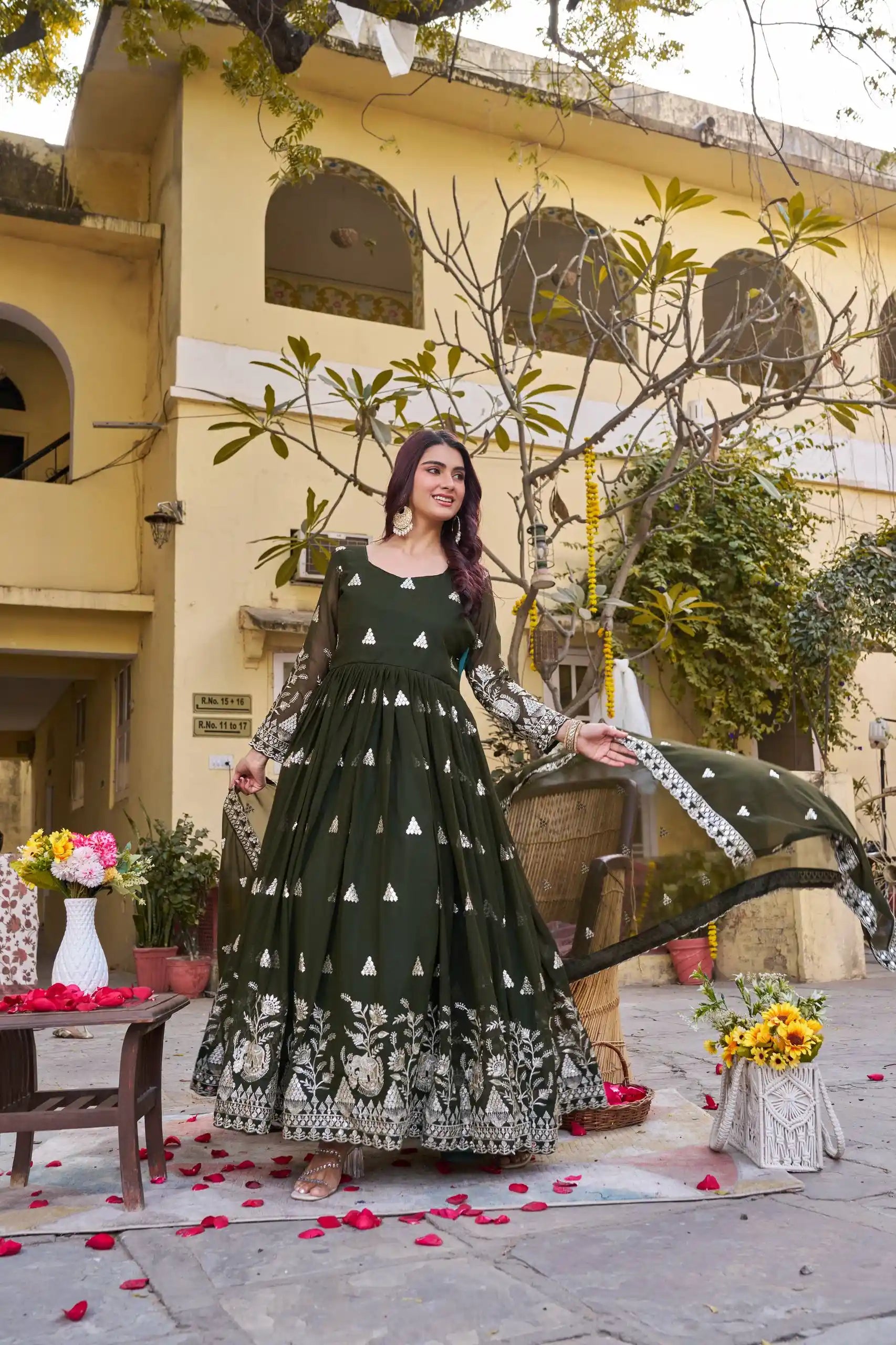 Woman in a green and black patterned dress standing in front of a building with decorative elements.